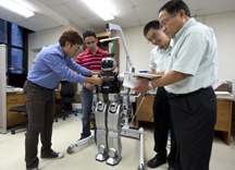 From left to right, Purdue electrical engineering doctoral students Andy Park and Rami Alazrai examine the wiring of a robot as associate professor Yung-Hsiang Lu and professor C.S. George Lee review specifications. (Purdue University photo/Mark Simons)