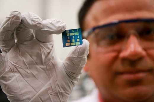 CAPTION University of Utah materials science and engineering associate professor Ashutosh Tiwari holds up a substrate layered with a newly discovered 2-D material made of tin and oxygen. Tiwari and his team have discovered this new material, tin monoxide, which allows electrical charges to move through it much faster than common 3-D material such as silicon. This breakthrough in semiconductor material could lead to much faster computers and mobile devices such as smartphones that also run on less power and with less heat. CREDIT Dan Hixson/University of Utah College of Engineering