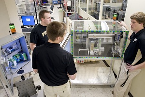 Purdue University is one of two teams from the United States selected to participate in the xplore New Automation Award 2012 contest in Germany. Aaron Burns (back left) and Ryan Streu (right) discuss the project, a hammer assembly machine, with fellow team member Jason Wintz. (Purdue University photo/Andrew Hancock)