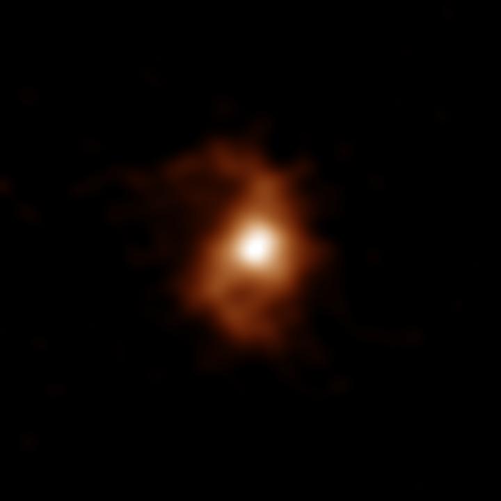 ALMA detected emissions from carbon ions in the galaxy. Spiral arms are visible on both sides of the compact, bright area in the center of the galaxy.  CREDIT ALMA (ESO/NAOJ/NRAO), T. Tsukui & S. Iguchi