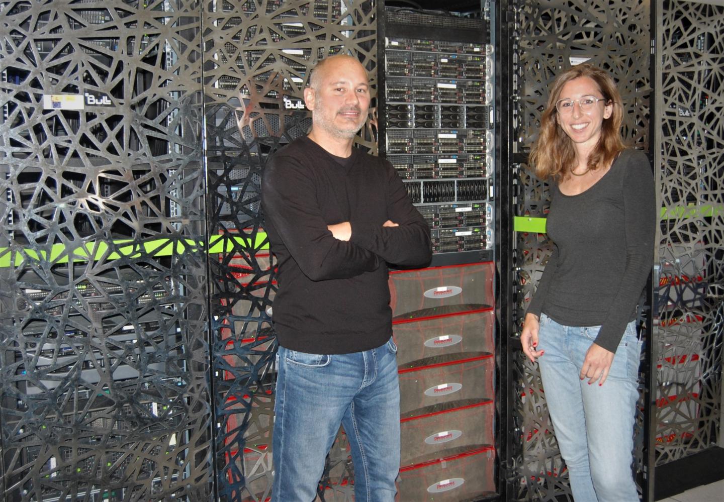 Sergi Beltran and Leslie Matalonga pictured in front of a supercomputer and servers that hosts the RD-Connect GPAP platform. The platform is located at the CNAG-CRG facilities in the Parc Cientific de Barcelona.