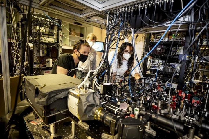 Dolev Bluvstein (from left), Mikhail Lukin, and Sepehr Ebadi developed a special type of quantum computer known as a programmable quantum simulator. Ebadi is aligning the device that allows them to create the programmable optical tweezers.  CREDIT Rose Lincoln/Harvard Staff Photographer