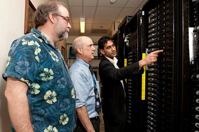 Newark High School teachers (from left) Robert McDowell and Stewart Dotts listen as University of Delaware professor Sandeep Patel shows them the computer he uses in his research. A new NSF grant will be used to purchase a smaller version of the supercomputer cluster for the high school.  Credit: Kathy F. Atkinson/University of Delaware